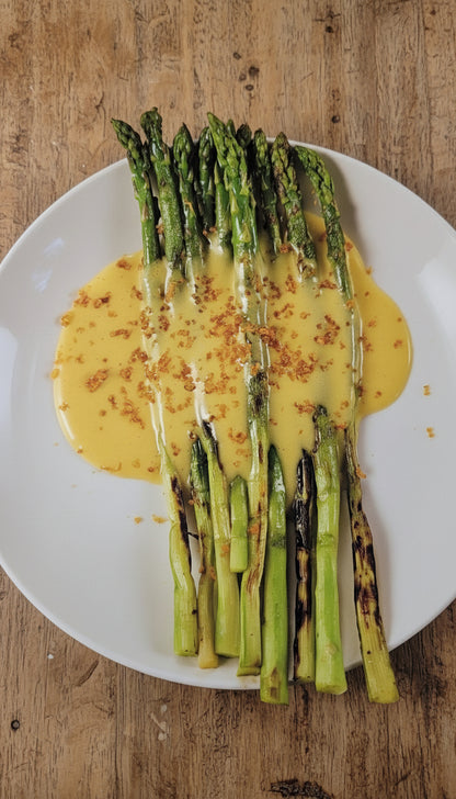 Asparagus with a yellow sauce on a plate, shown in an open book.