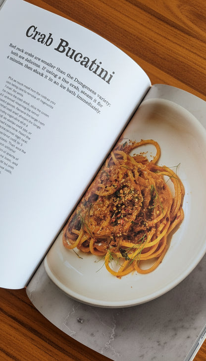 Open cookbook showing a dish of Crab Bucatini on a plate.